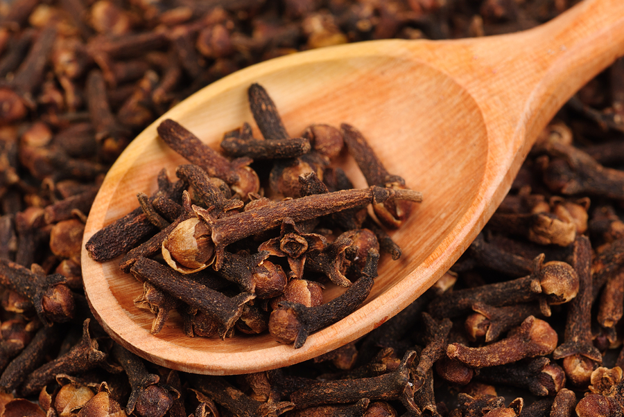 Cloves (spice) and wooden spoon close-up food background