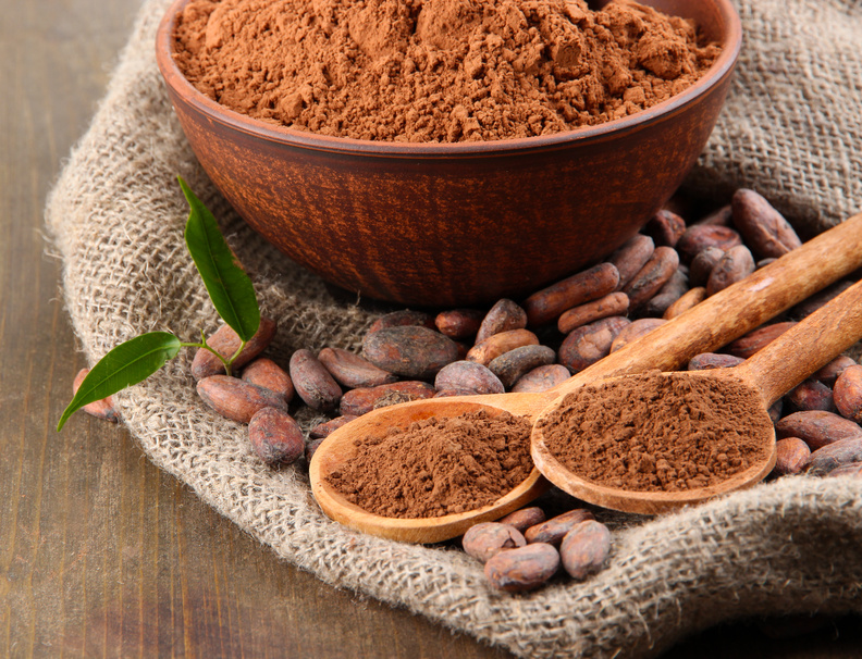 Cocoa powder and cocoa beans on wooden background