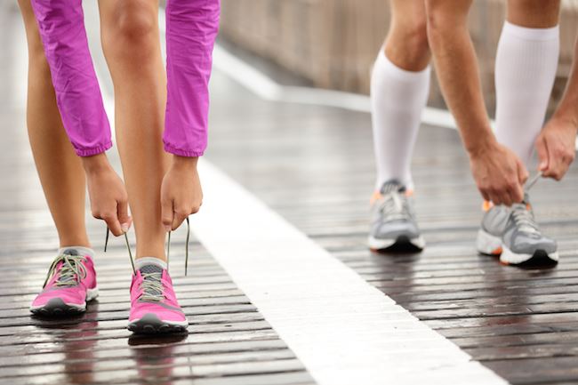 Runner feet. Running couple closeup of running shoes. Woman barefoot running shoes in foreground. Co