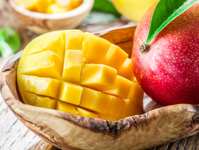 Mango fruit and mango cubes on the wooden table.