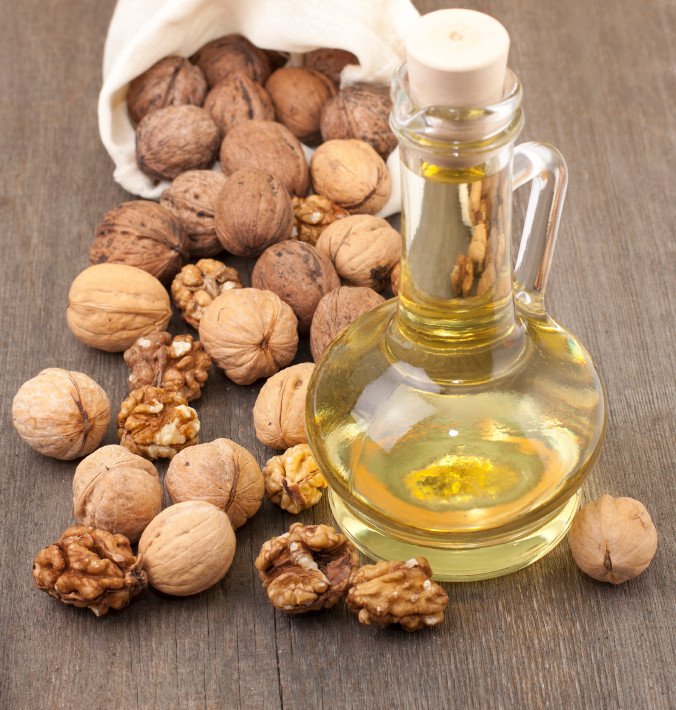 Walnut oil and walnuts on a wooden table.